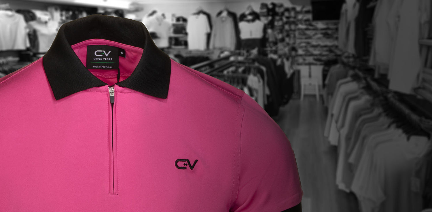 Pink polo shirt with black collar and logo in a clothing store setting